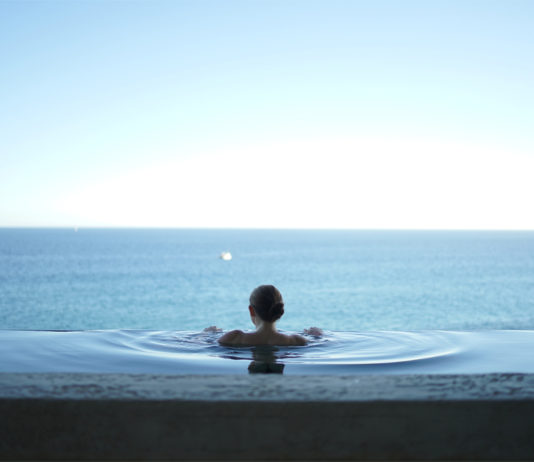 mujer mirando al horizonte en una piscina con cloración salina